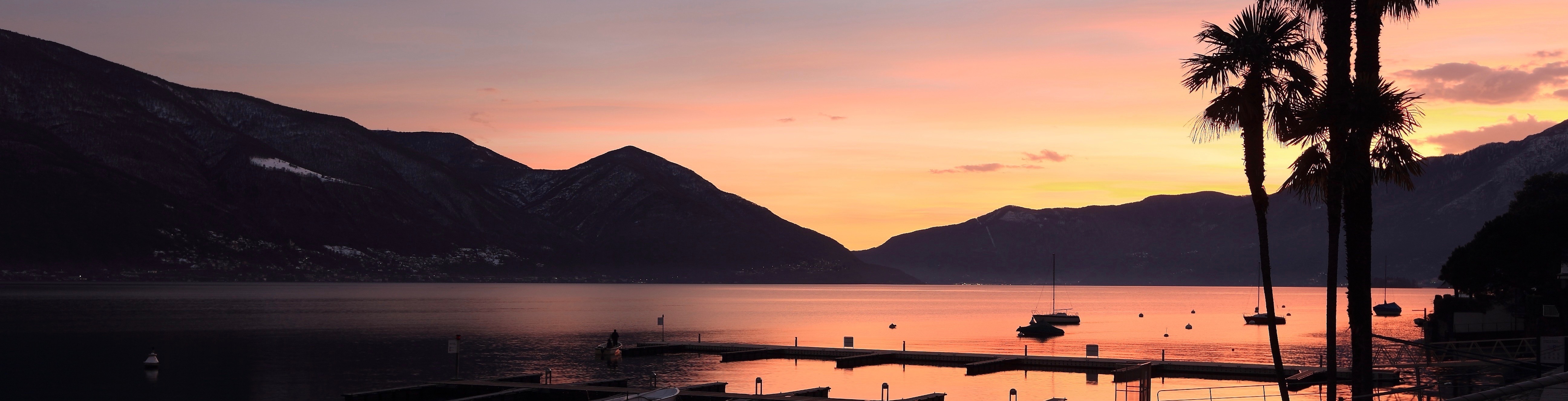 Sunset over Lago Maggiore with palms and mountains in silhouette
